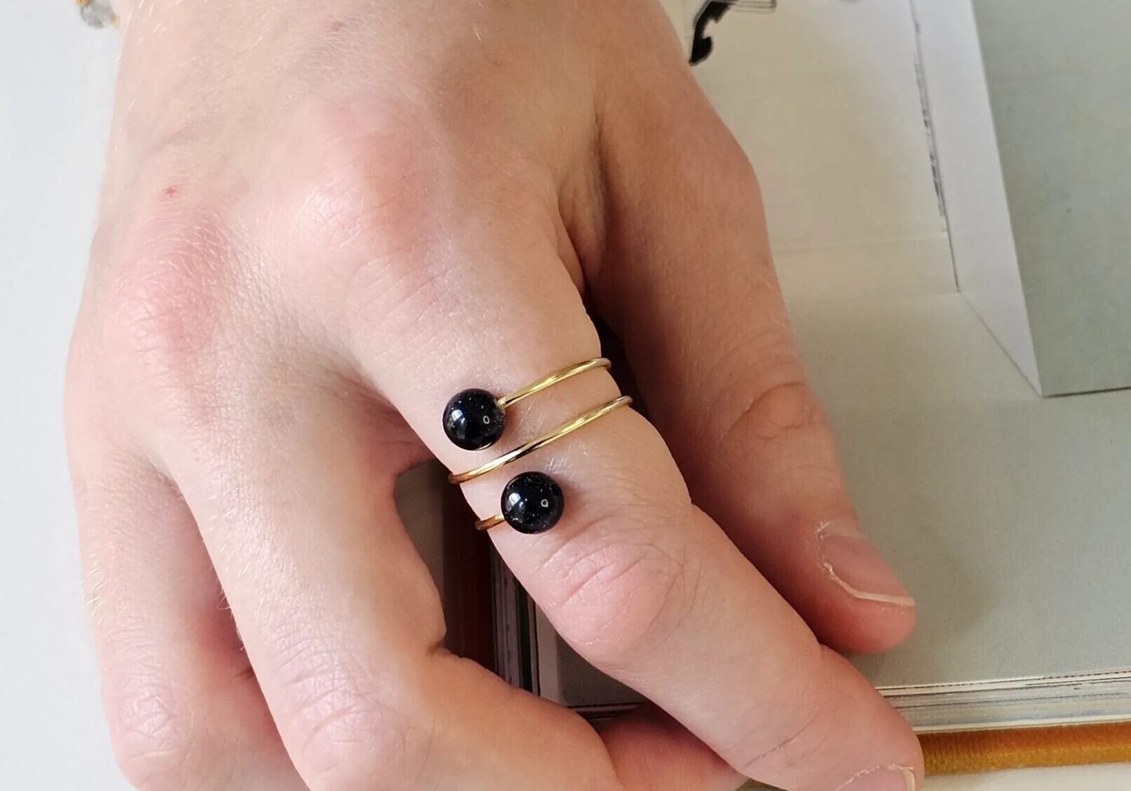 Hand wearing gold ring with black beads