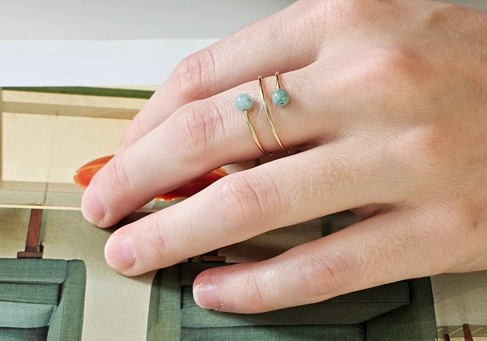 Hand wearing gold ring with turquoise beads